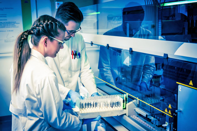 Bild 2: Blick in das Serologie-Labor am CVUA Stuttgart. Ein Labormitarbeiter und eine Labormitarbeiterin beladen gemeinsam ein Laborgerät mit Blutproben, die untersucht werden sollen.