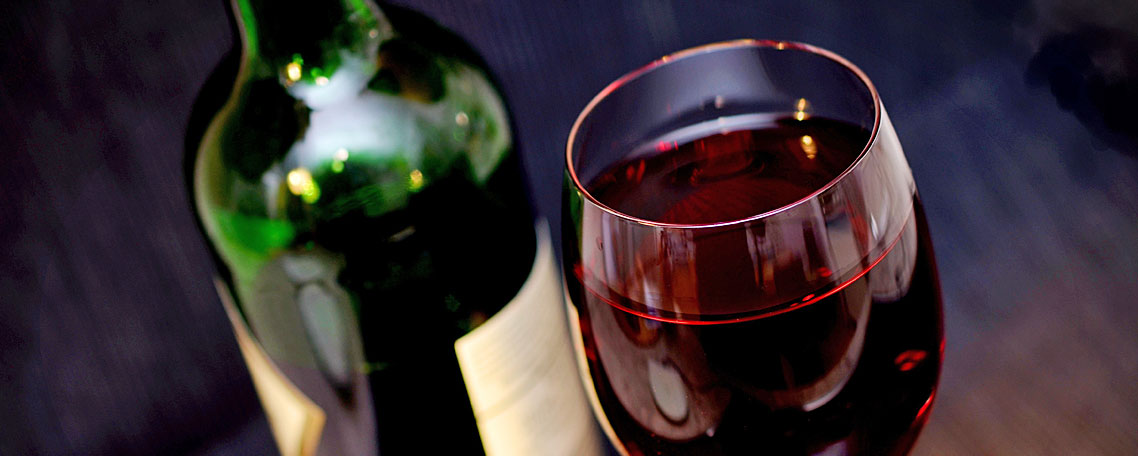 Eine gr�ne Weinflasche steht neben einem Glas mit Rotwein; Quelle: Pixabay.