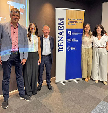 Mehrere Personen stehend vor dem Plakat des RENAEM, welches neben dem Schriftzug die Logos der beteiligten Institutionen abbildet.